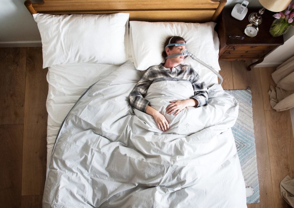 Obstructive Sleep Apnea Woman sleeping bed wearing a CPAP mask