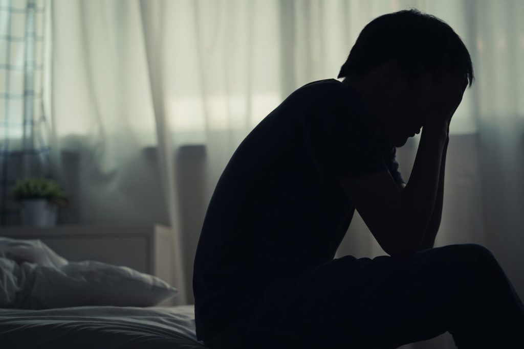 Somniphobia: Understanding the Fear of Sleep A man with Somniphobia sittting on edge of bed